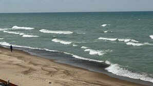 Une plage avec des vagues et une personne qui se promène.