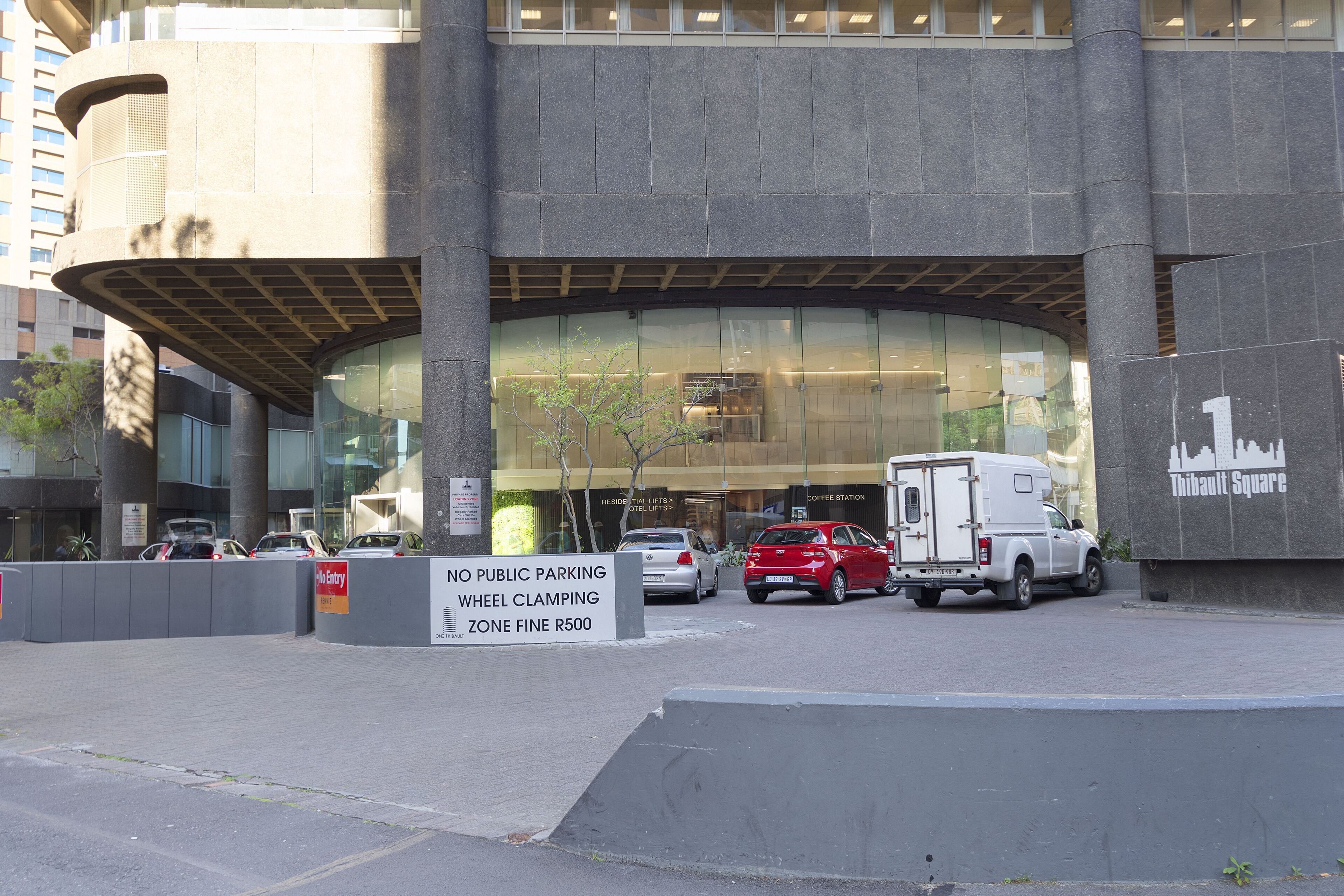 A building with a curved entrance, a no public parking sign, and a vehicle parked in front.