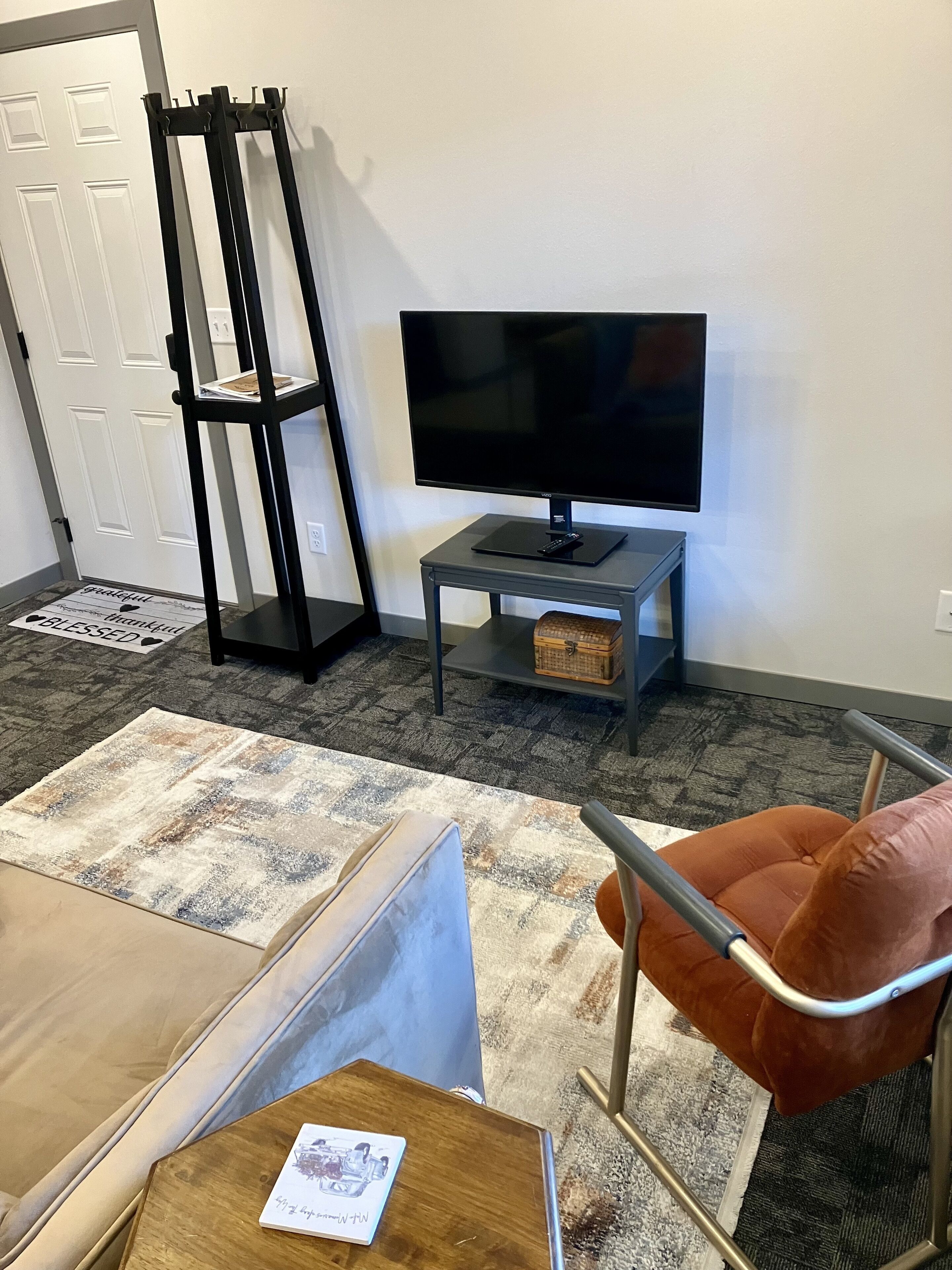 Un salon avec un canapé, une table basse, un téléviseur posé sur un meuble et un fauteuil.