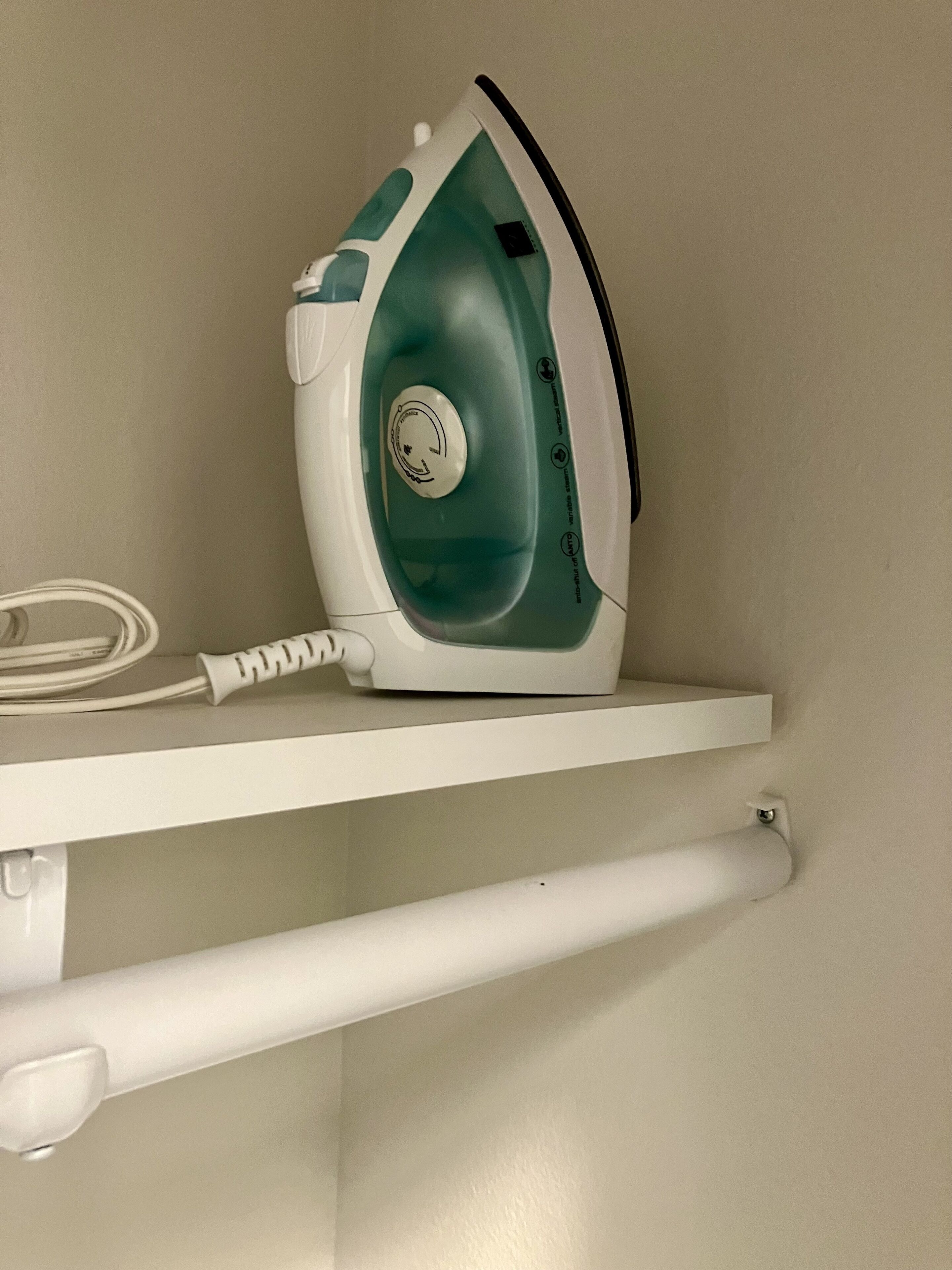 Un objet en fer, de couleur bleu-vert et blanc, posé sur une étagère blanche.