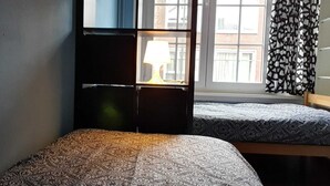 A room with two beds, a window with curtains, and a lamp on a bedside table. - Room-room With 2 Separated Beds (Mortsel)