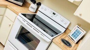 A kitchen with a microwave, oven, and a small cabinet with utensils. - Beautiful 2 bedroom unit across from UF stadium
 (Gainesville)