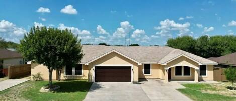 A single-story house with a garage, a front lawn, and a tree.