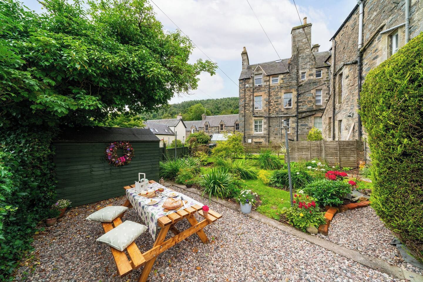 A stone building with a garden patio and a table set for dining.