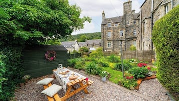 A stone building with a garden patio and a table set for dining.