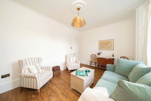A living room with striped armchairs, a light-colored sofa, a wooden coffee table, and a hanging light fixture. - Dreamy Town House Apartment in Dunkeld (Dunkeld)