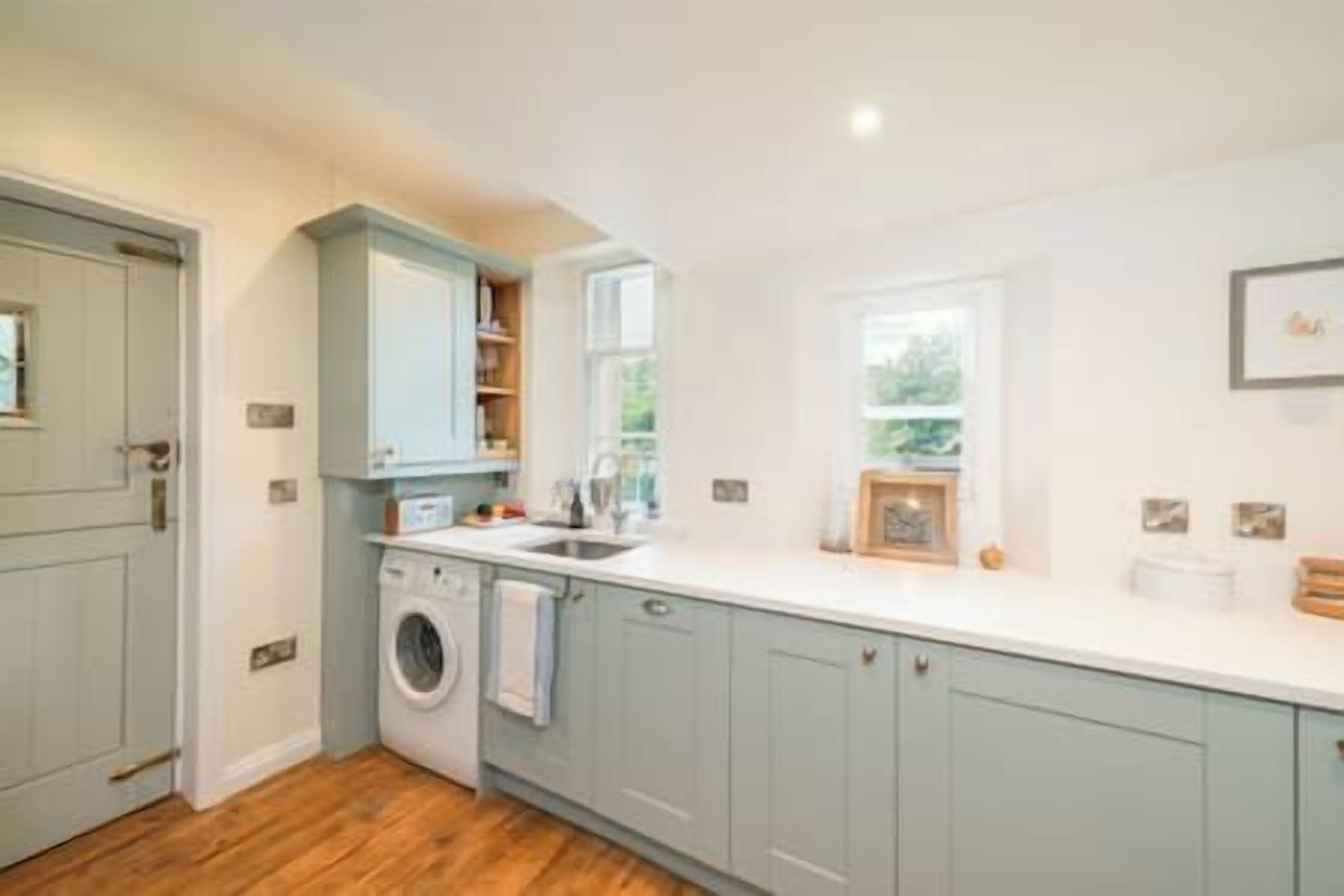 A kitchen with light blue cabinets, a washing machine, and a window providing natural light.
