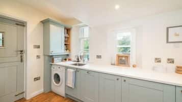 A kitchen with light blue cabinets, a washing machine, and a window providing natural light.