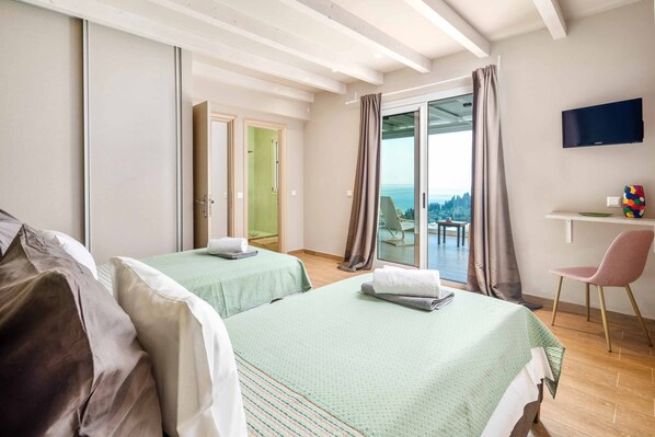 Une chambre d’hôtel avec deux lits, un bureau, une télévision et un balcon avec vue.