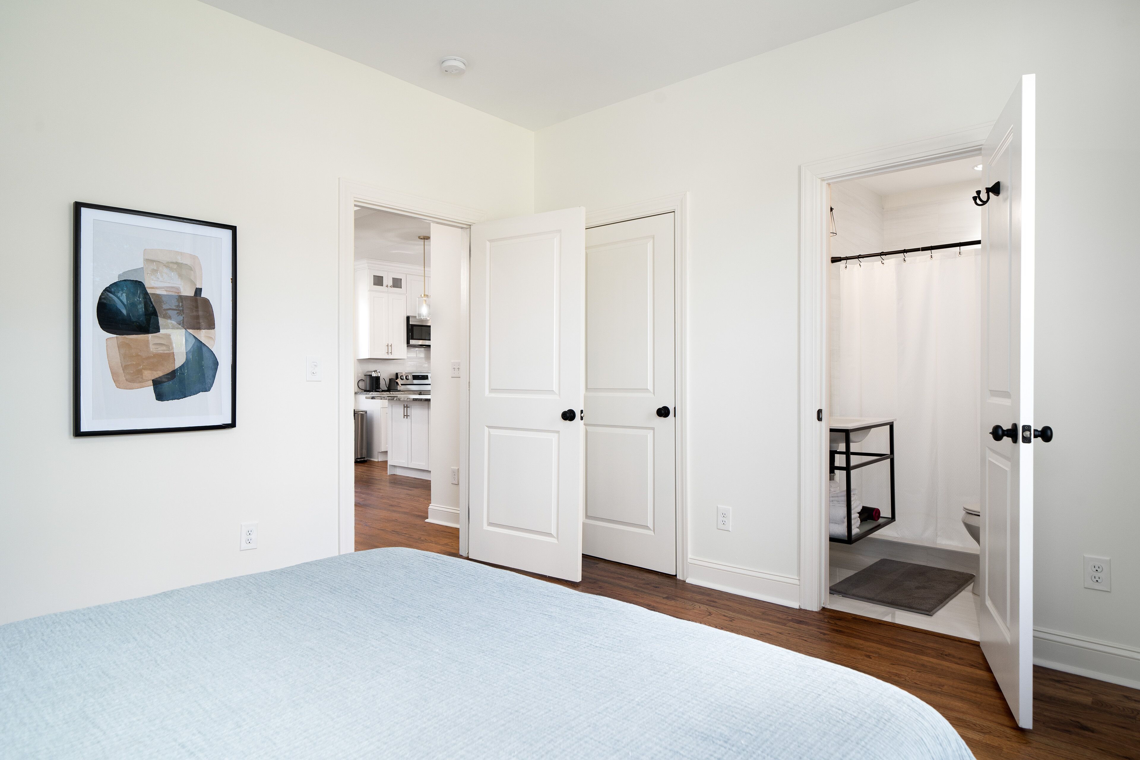 Une chambre à coucher avec un lit, une porte donnant sur une salle de bain et un couloir.