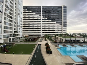 Um hotel moderno com uma piscina grande, área de estar ao ar livre e vista para o horizonte da cidade.