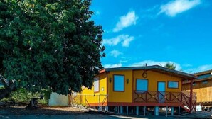 A yellow building with a balcony, situated by a clear blue water body. - La Posita Beach House  (Cabo Rojo)