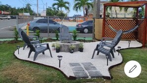 An outdoor patio with two lounge chairs, a fire pit, and a hammock. - La Posita Beach House  (Cabo Rojo)