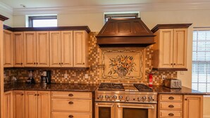 Cucina con pensili in legno, piano cottura a gas e zoccolo piastrellato.