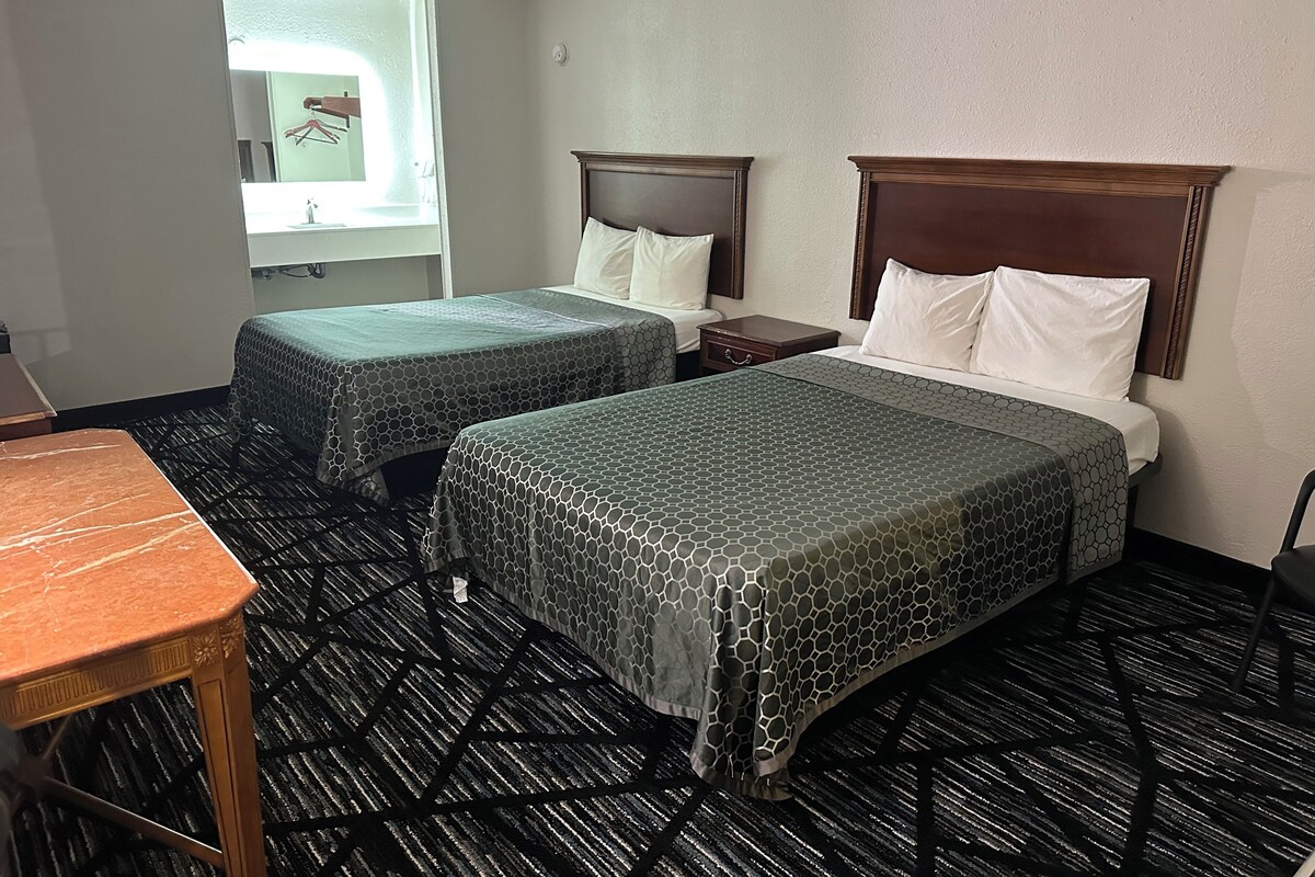 Une chambre d’hôtel avec deux lits, une petite table et une fenêtre.