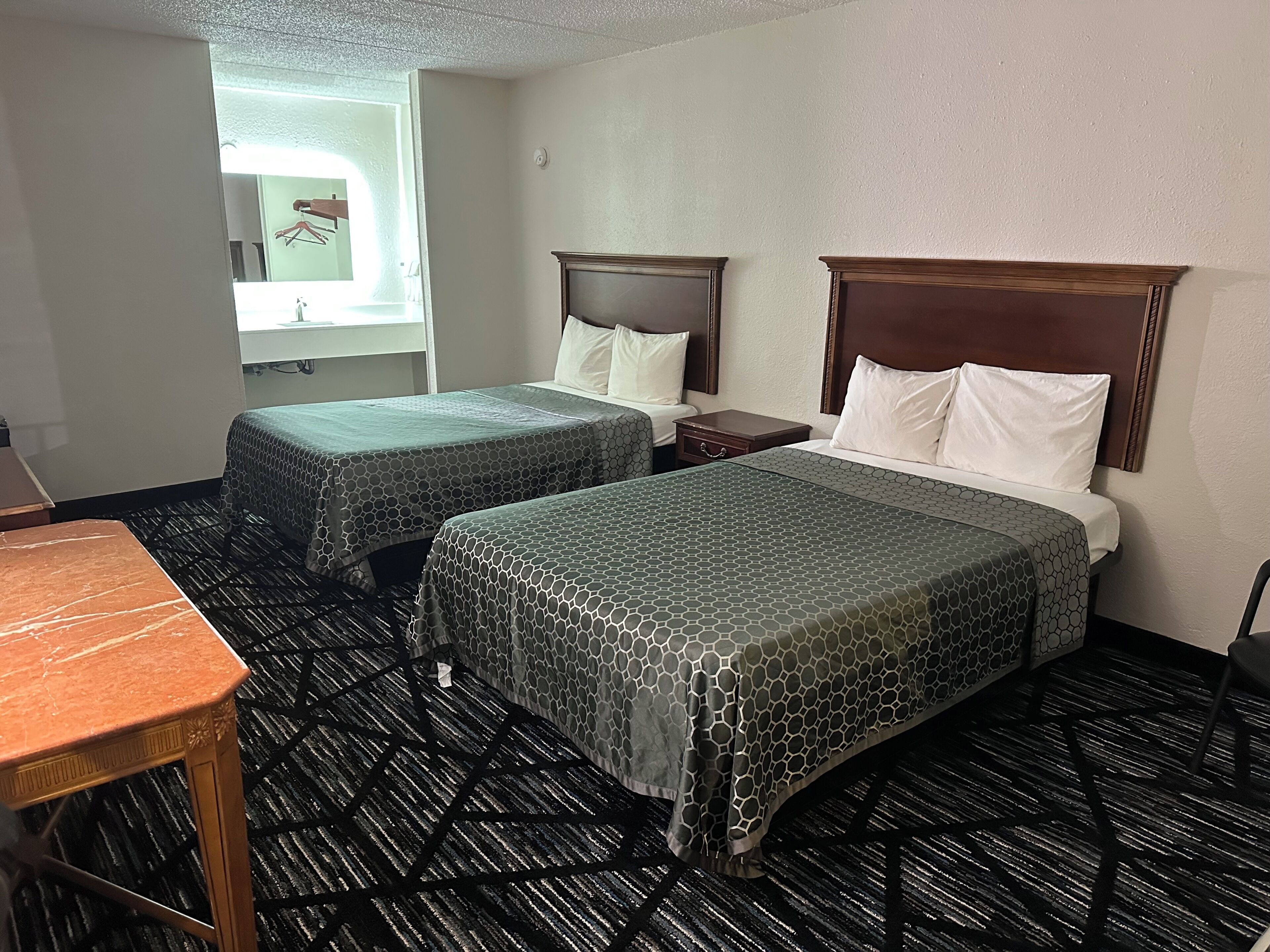 Habitación de hotel con dos camas, una mesita y un ventanal.