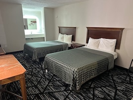 Habitación de hotel con dos camas, una mesita y un ventanal.