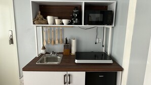Eine kleine Küche mit Einbau-Mikrowelle, Kaffeemaschine und Spüle.