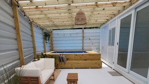 Eine überdachte Terrasse mit einer hölzernen Bank, einem kleinen Tisch und einem weißen Sofa.