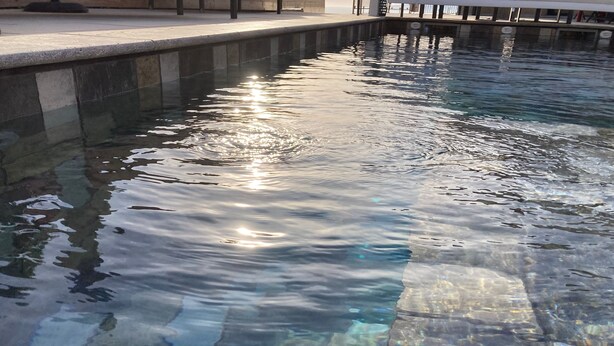 A clear pool with sunlight reflecting off the water's surface.