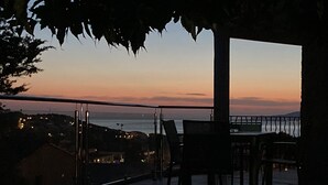 An outdoor seating area with a view of the ocean at dusk.