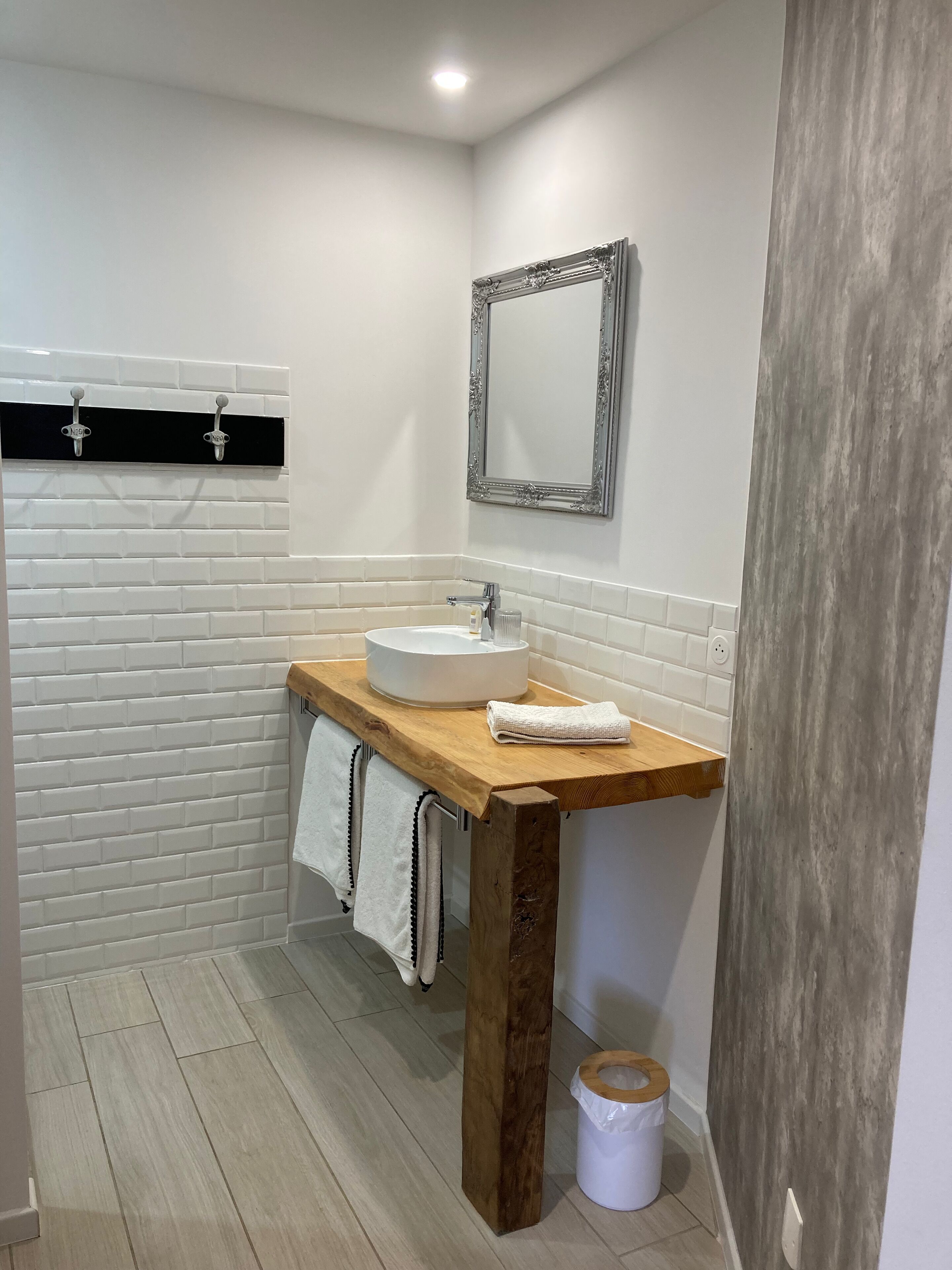 Un baño con lavamanos blanco, encimera de madera y espejo con un marco decorativo.