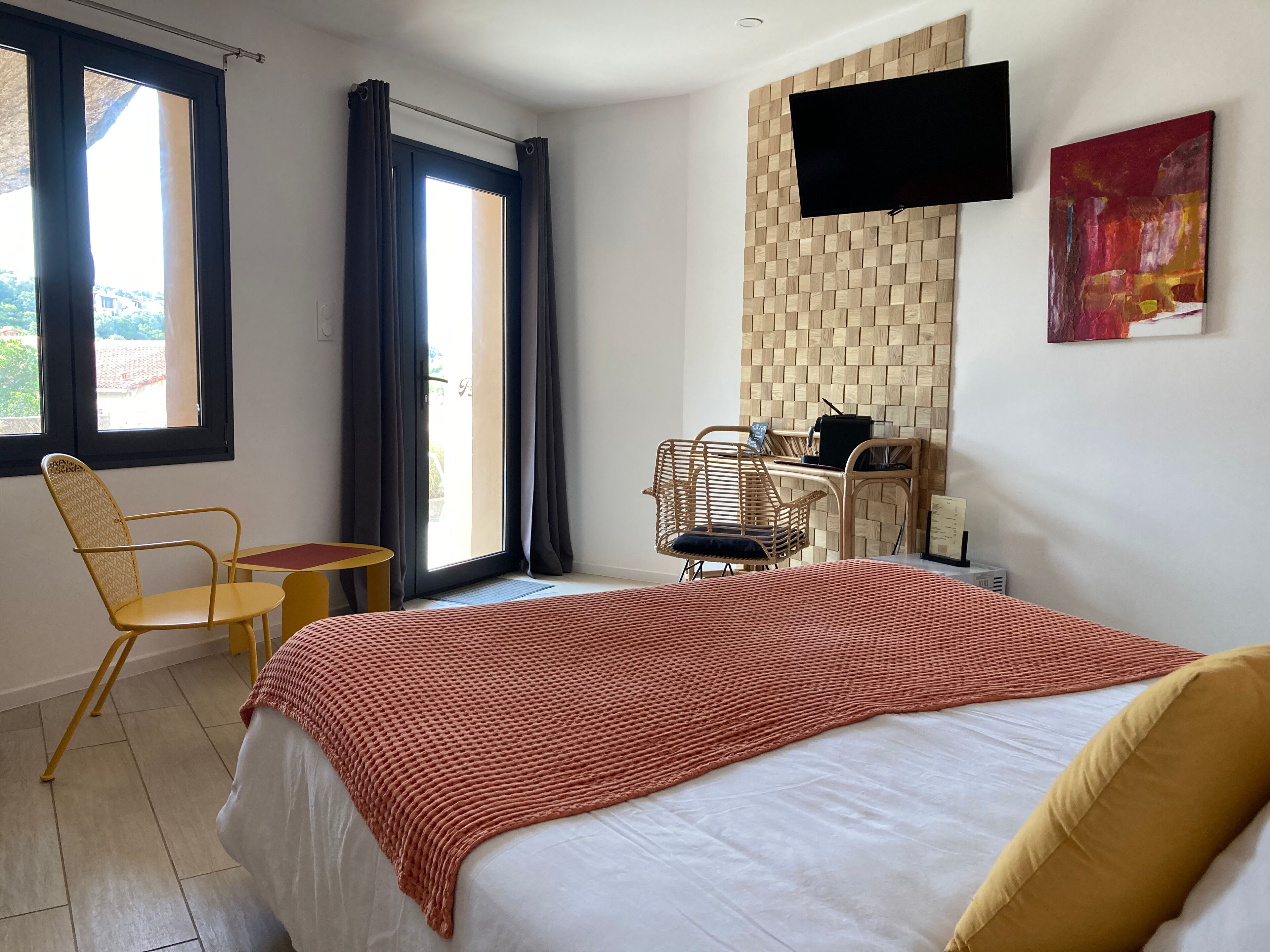 Hotelkamer met een bed, een bureau, een stoel, een televisie en een raam met gordijnen.