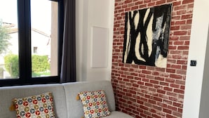 A grey sofa with patterned cushions against a brick wall with a large abstract painting.