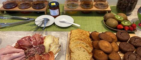 A table with various food items including meats, bread, cookies, and fruits.