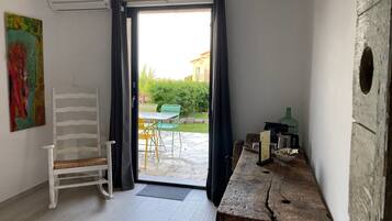 A room with a wooden table, a chair, a small table with a bowl, and a view of the outside.