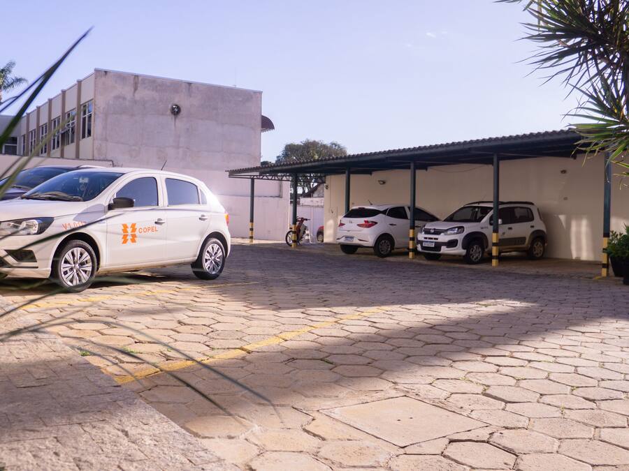 Un área de estacionamiento con varios autos, incluyendo un auto blanco con un logo visible.