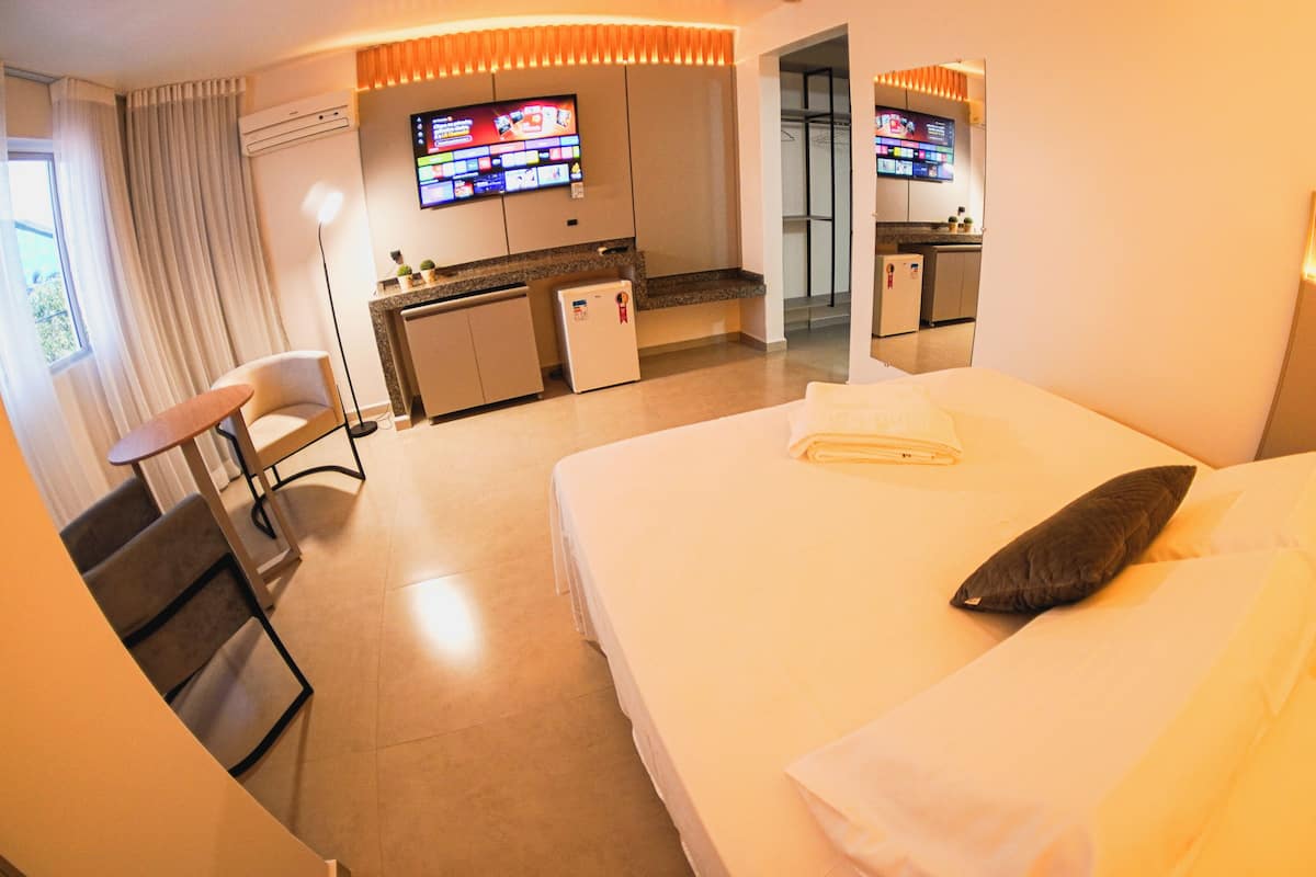 Ein Hotelzimmer mit Bett, Schreibtisch, Stuhl, Fernseher und Spiegel.