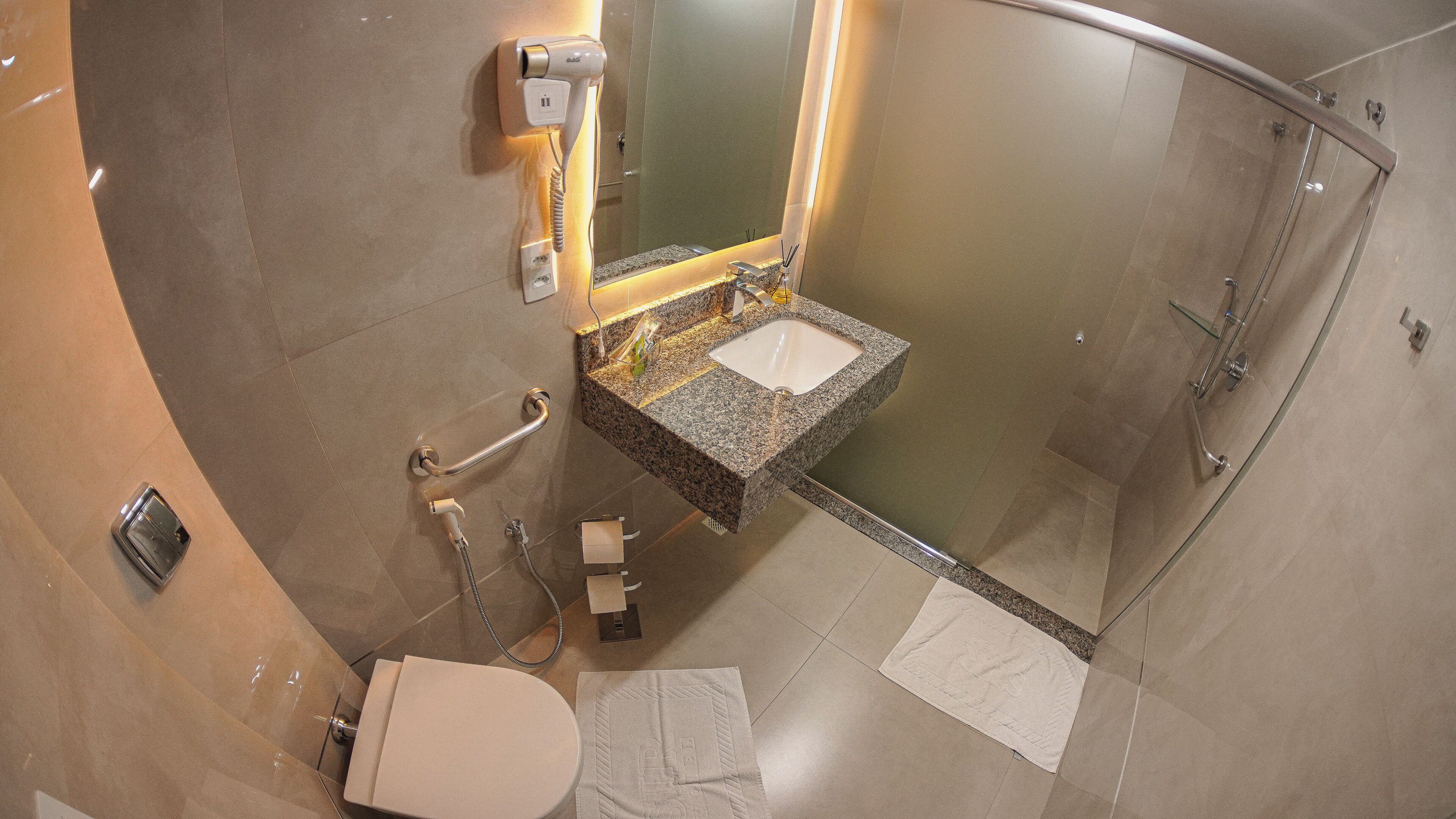 A modern bathroom with a toilet, sink, and shower.