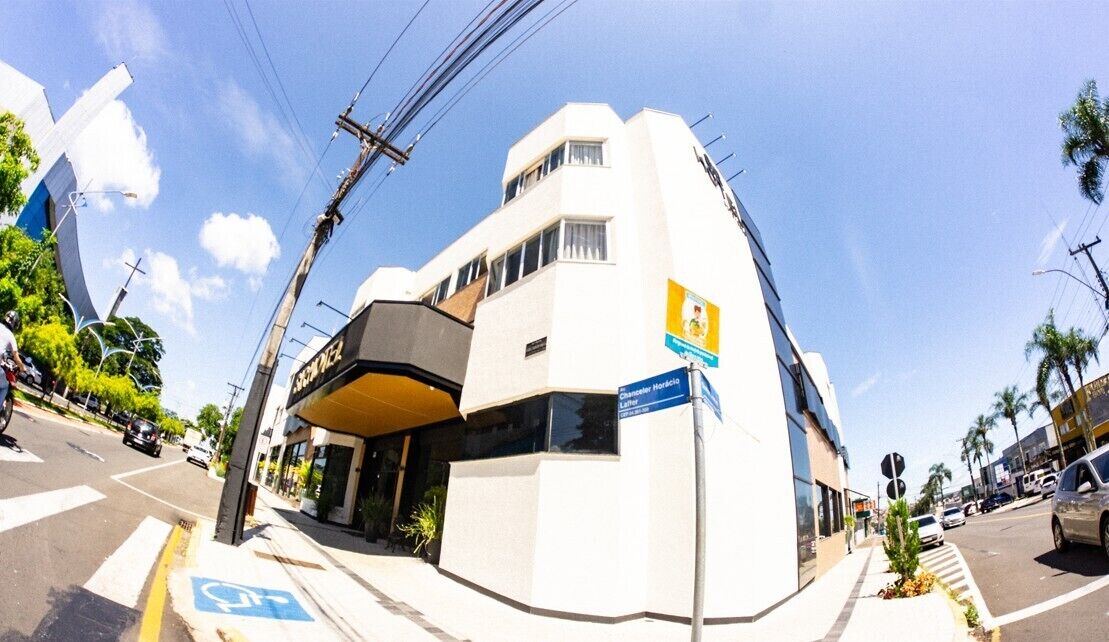 Un edificio moderno con fachada blanca, un letrero azul que indica un negocio y una rampa accesible para sillas de ruedas.