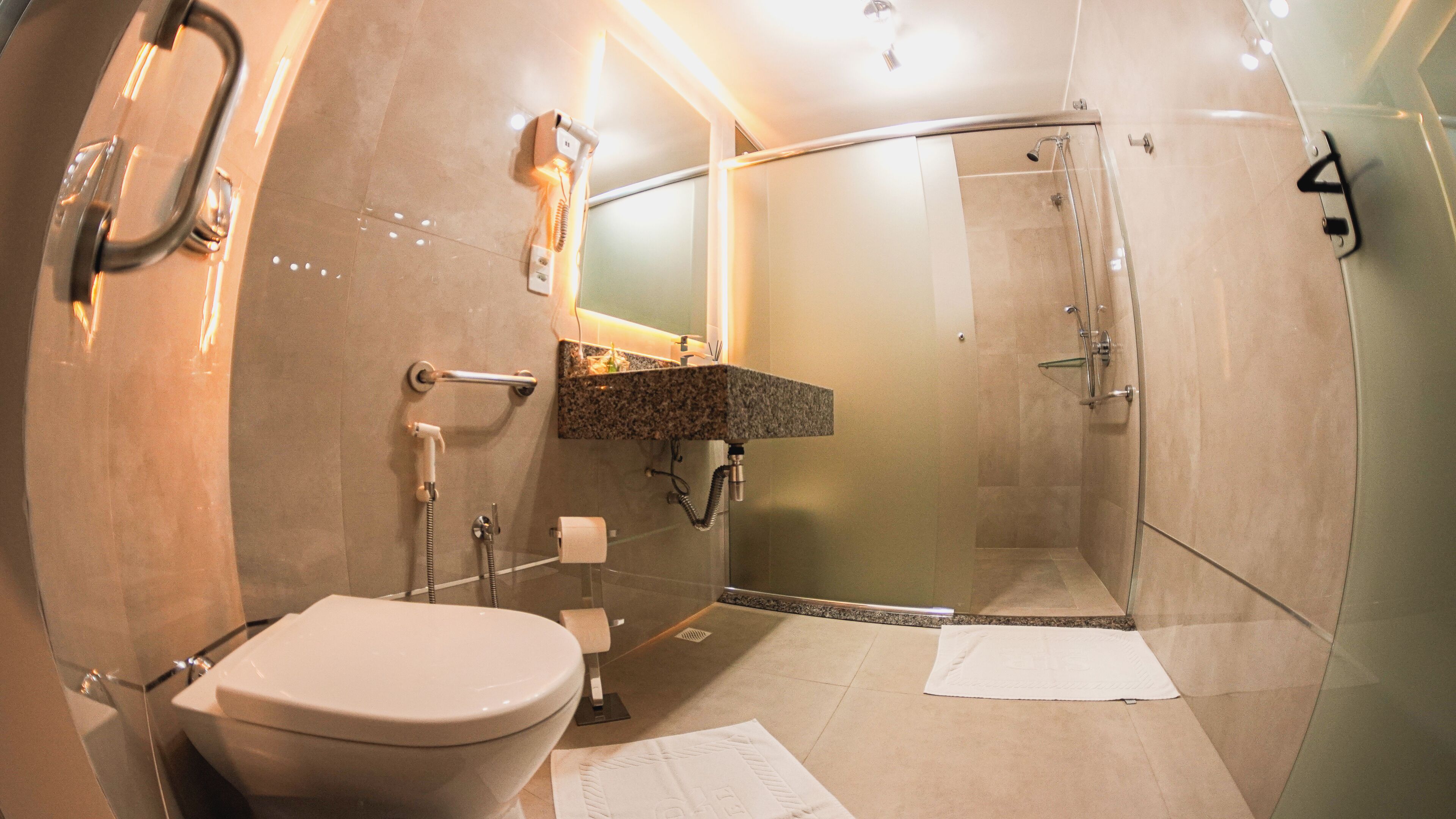 Un baño moderno con inodoro, lavamanos y ducha.