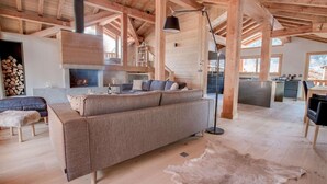 Un grand espace de vie comprenant un canapé, une cheminée, une table à manger et une cuisine en arrière-plan.