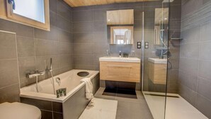 Une salle de bain moderne équipée d’une baignoire, de toilettes, d’une douche à parois de verre et d’un meuble-lavabo avec un miroir.