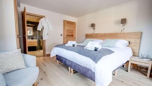 Une chambre à coucher avec un grand lit, une tête de lit en bois, des tables de chevet, une chaise et un miroir.