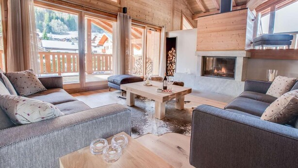 Un salon chaleureux aux murs en bois et doté d’une cheminée, comprenant un ensemble de canapés et une table basse.