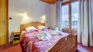 A wooden bed with a heart-shaped headboard, two bedside tables, and a window with curtains. - 1st floor, view ski slopes, balcony, fireplace or stove, parking, tv, 118m², Morzine (Morzine)