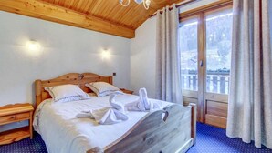 A wooden bed with a headboard, two bedside tables, and a chandelier. - 1st floor, view ski slopes, balcony, fireplace or stove, parking, tv, 118m², Morzine (Morzine)