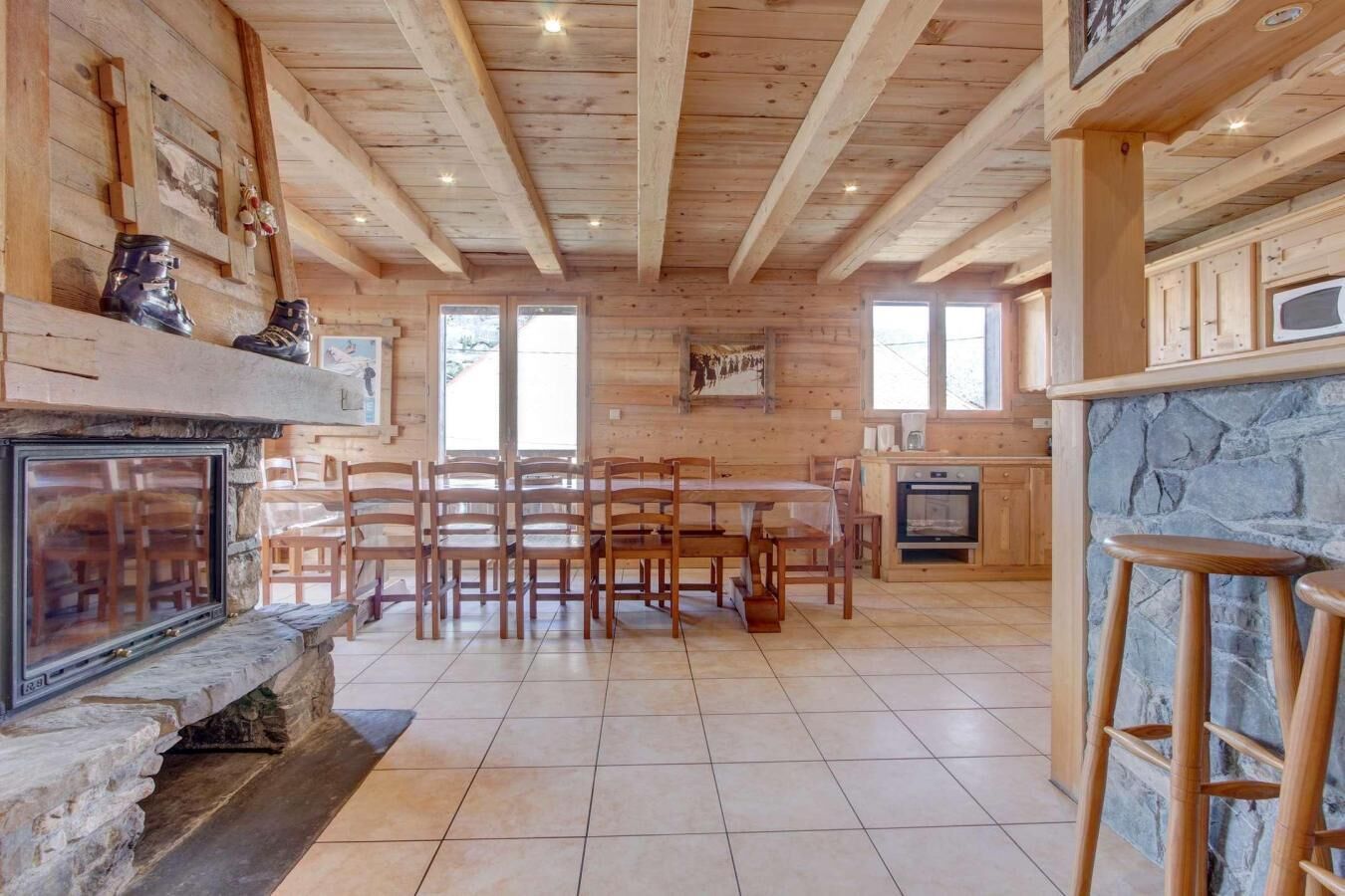 A cozy cabin interior with a stone fireplace, wooden dining table, and chairs.