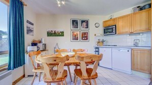A kitchen with wooden chairs, a dining table, a microwave, and a dishwasher. - 50m from ski slopes, 2nd floor, view mountain, balcony, tv, ski locker, 38m², Morzine (Morzine)