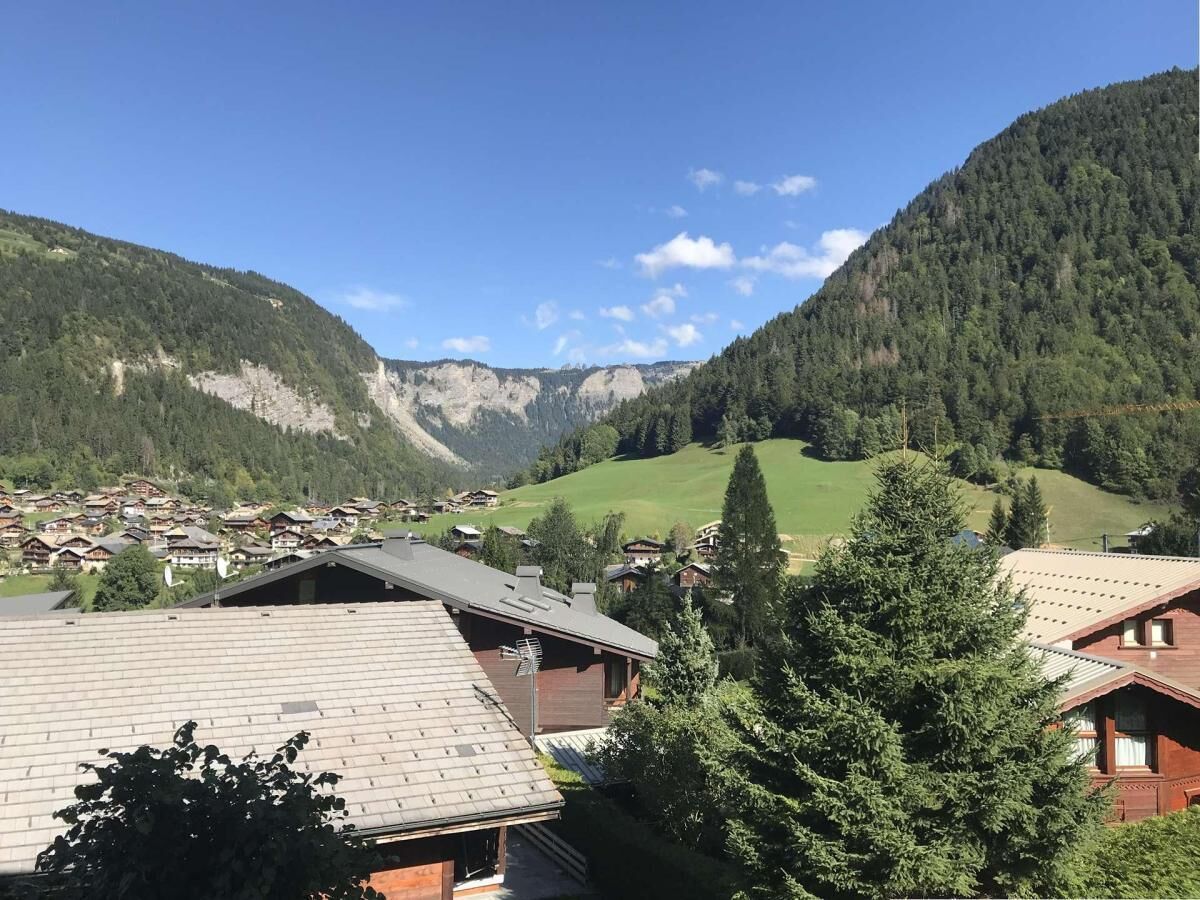 Ein dorfähnliches Bergdorf mit traditionellen Holzhäusern, blauem Himmel und üppigem Grün.
