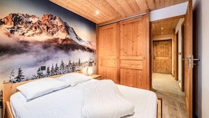 Camera da letto con un affresco raffigurante montagne, un letto di legno e un armadio.