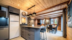 Una cucina moderna con isola centrale, zona pranzo con tavolo e sedie, e parete decorata con pietra.