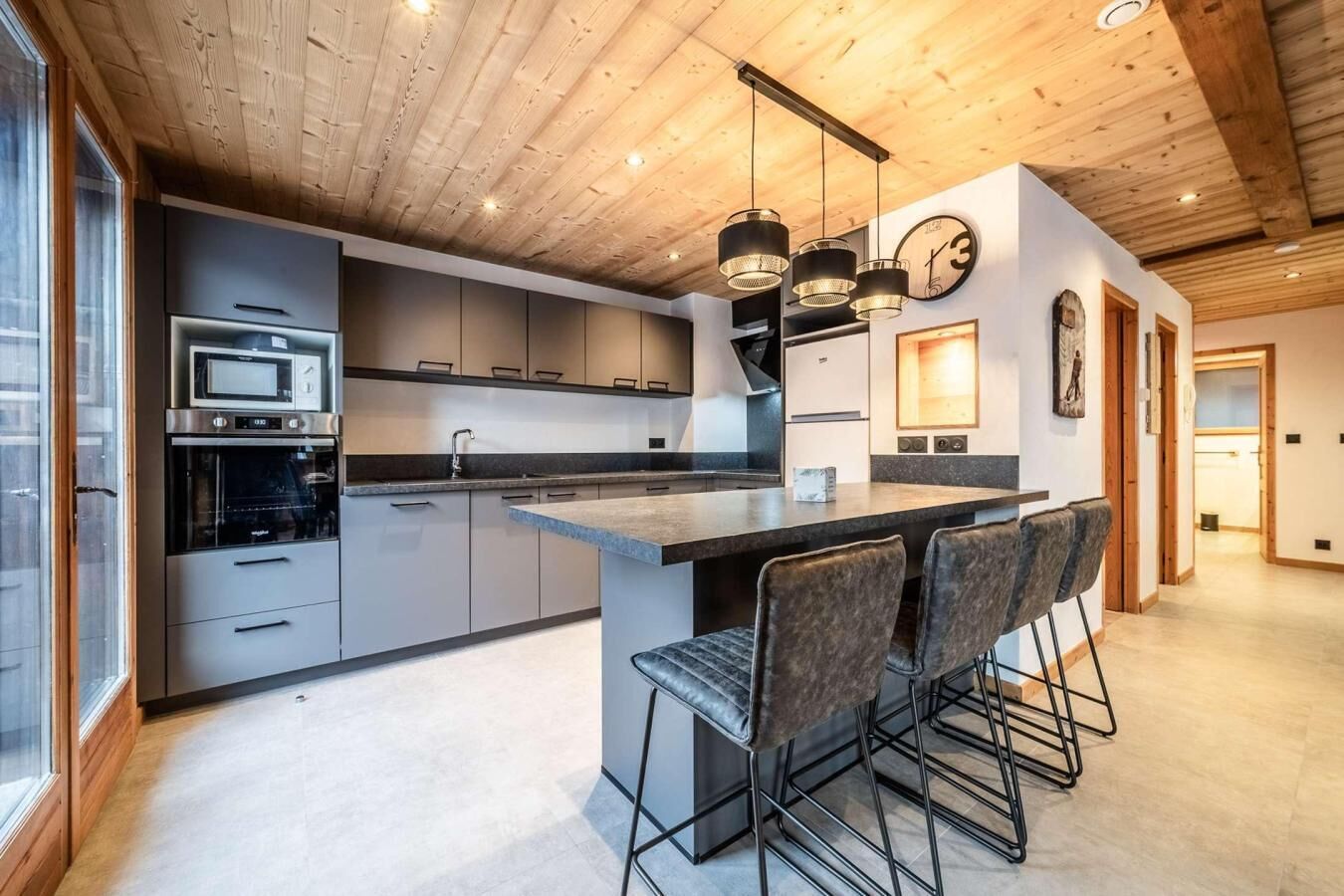 Una cocina moderna con una isla central, taburetes de bar e iluminación colgante.