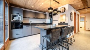 Una cucina moderna con isola centrale, sgabelli da bar e illuminazione a sospensione.