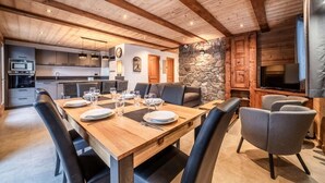 Una cucina moderna con elettrodomestici integrati, un'area pranzo con tavolo e sedie in legno e una parete decorata con pietra.