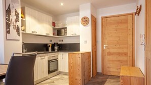 A compact kitchen with white cabinets, a black countertop, and a wooden door. - 100m from ski slopes, Ground floor, terrace, parking, tv, 31m², Morzine (Morzine)